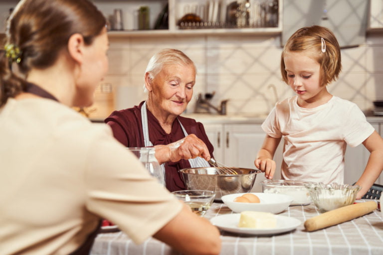 a person and a couple of children sitting at a table with food