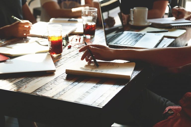 a person sitting at a table with a laptop and other people