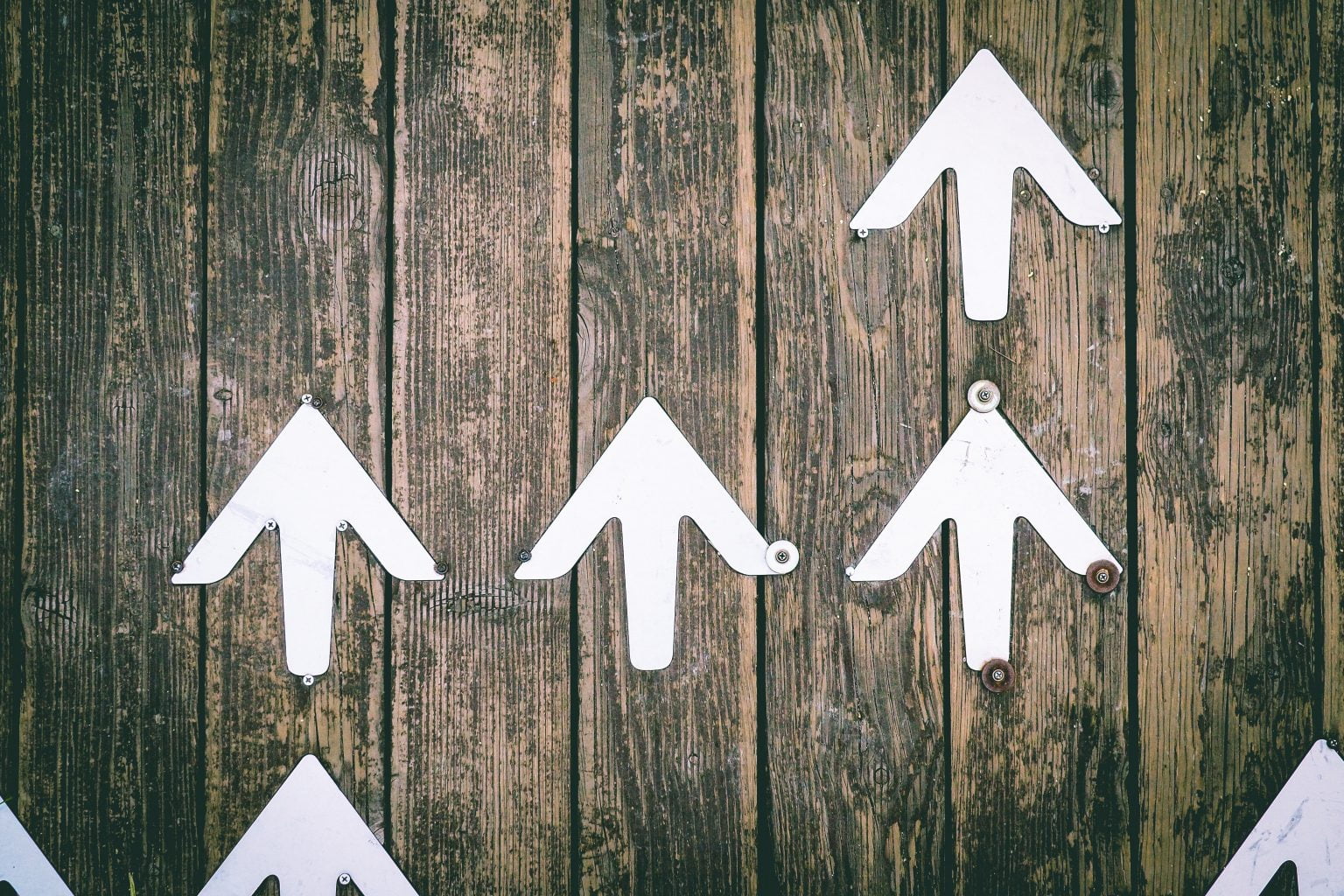 a group of white arrows pointing in opposite directions on a wooden board
